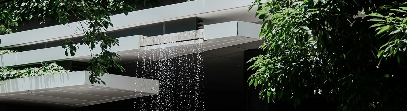 Architettura moderna in cemento con cascata d'acqua e vegetazione in primo piano